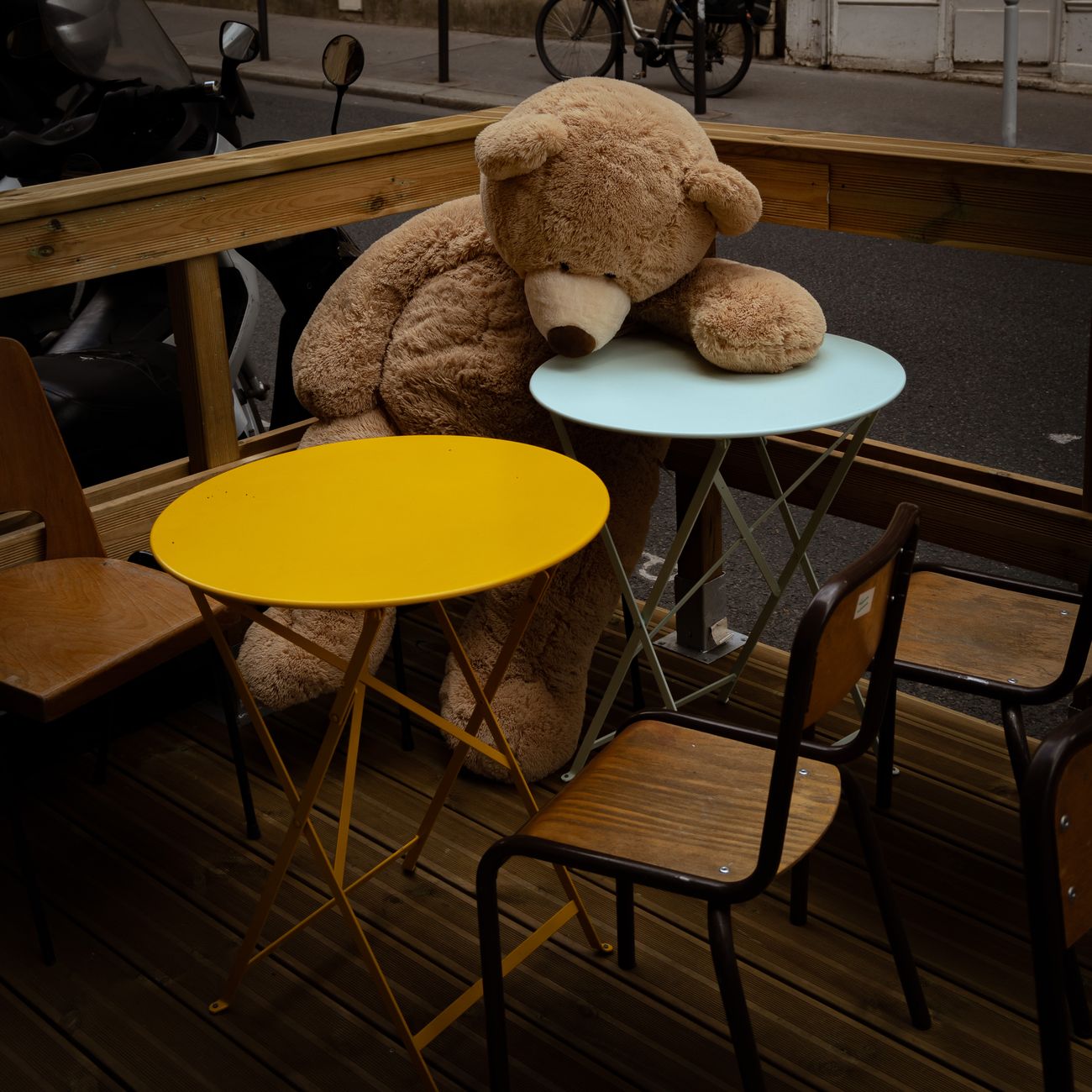Sample: a plush teddy bear on a cafe table with a busy street behind it