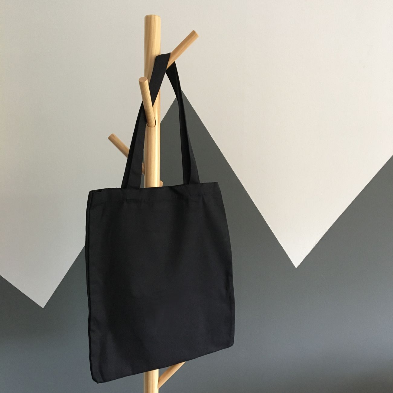 Sample: a black canvas tote hanging on a wooden rack