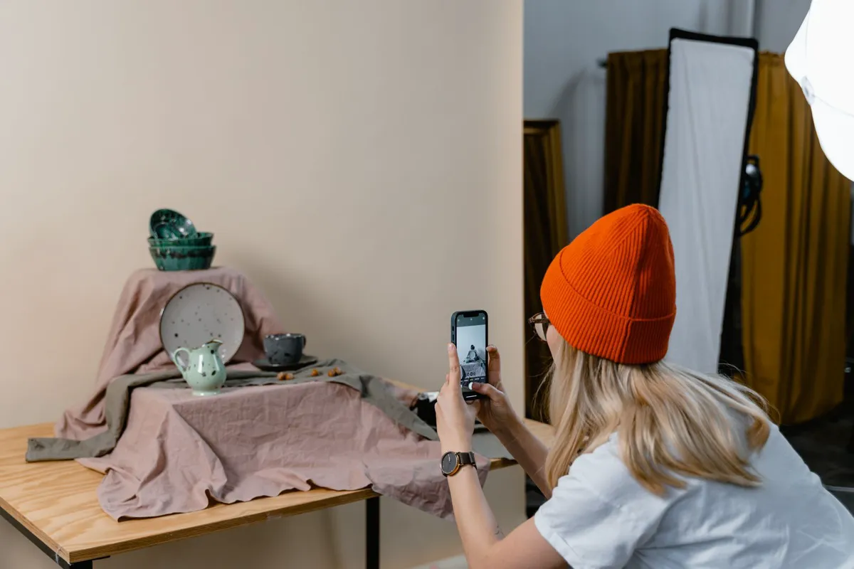 Seller photographing tableware with a smartphone in a studio